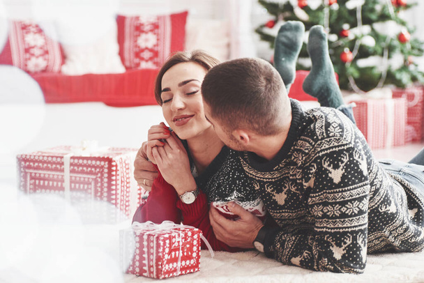 Feeling pleasure. Lovely young couple lying on the floor of living room at new year time with gift boxes. - Foto, Imagem