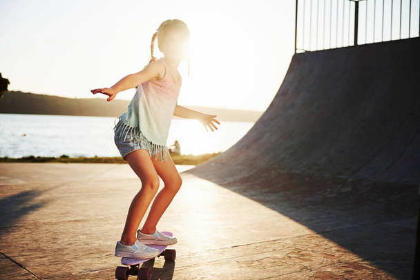 First attempts. Sunny day. Kid have fun with skate at the ramp. Cheerful little girl. - Foto, immagini