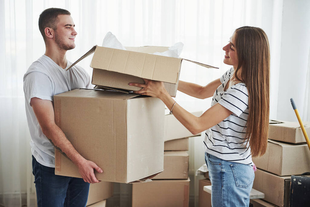 A lot of boxes. Cheerful young couple in their new apartment. Conception of moving. - Foto, Imagem