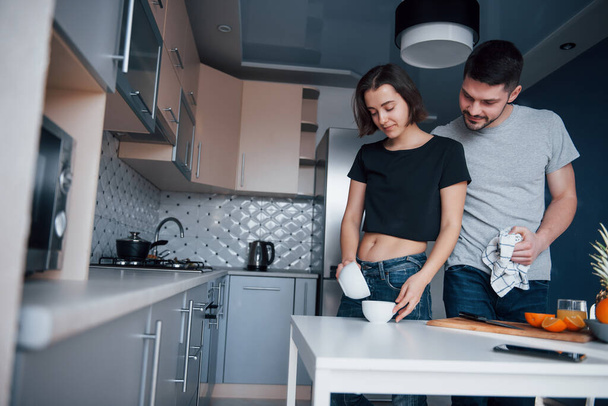Pouring the water. Young couple in the modern kitchen at home at their weekend in the morning time. - Fotografie, Obrázek