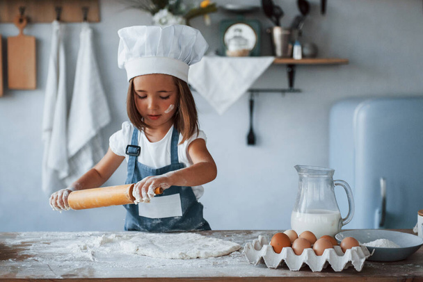 Cute kid in white chef uniform preparing food on the kitchen. - Φωτογραφία, εικόνα