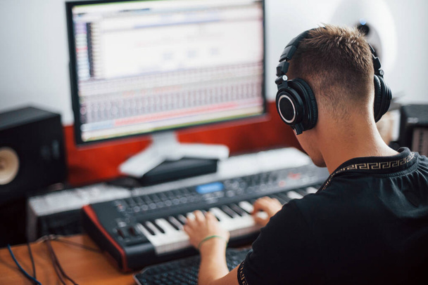 Sound engineer in headphones working and mixing music indoors in the studio. - Foto, imagen