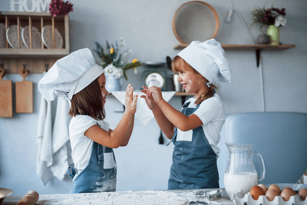 Having fun during the process. Family kids in white chef uniform preparing food on the kitchen. - Foto, Imagem