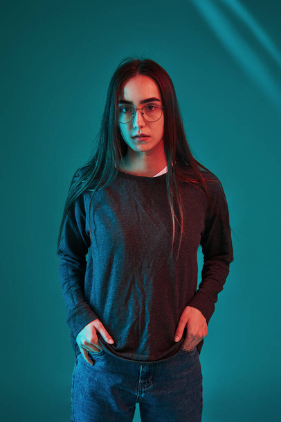Black jacket. Studio shot indoors with neon light. Portrait of beautiful young girl. - Фото, зображення