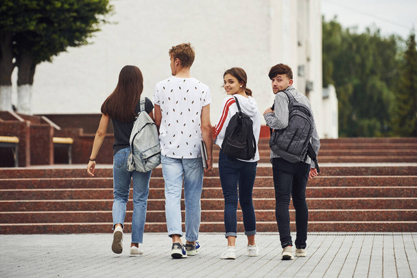 Looking behind. Rear view. Group of young students in casual clothes near university at daytime. - Foto, Imagem