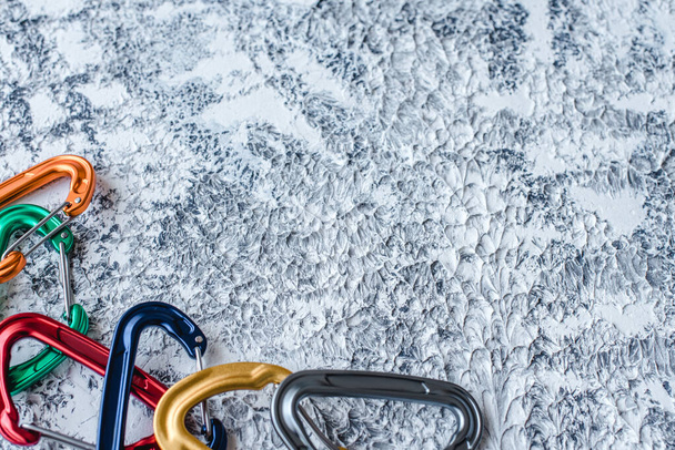 On the edge of picture. Isolated photo of climbing equipment. Part of carabiner lying on the white and grey colored surface. - 写真・画像