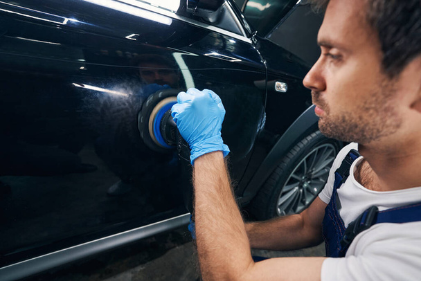 Car repair shop mechanic working away scratches with polisher - Foto, Imagen