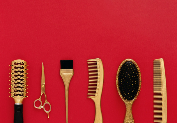 Background with hairdressing tools on red. Hair salon accessories gold, hair combs, scissors. Banner and template for design with space for text. - Photo, Image