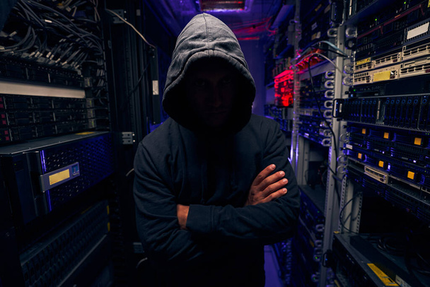 Мрачный человек, стоящий между стойками с компьютерным оборудованием - Фото, изображение