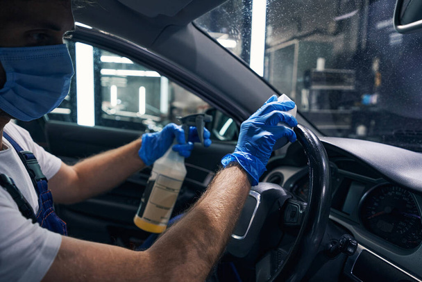 Male wiping steering wheel of car from cleaning fluid - Foto, Imagem