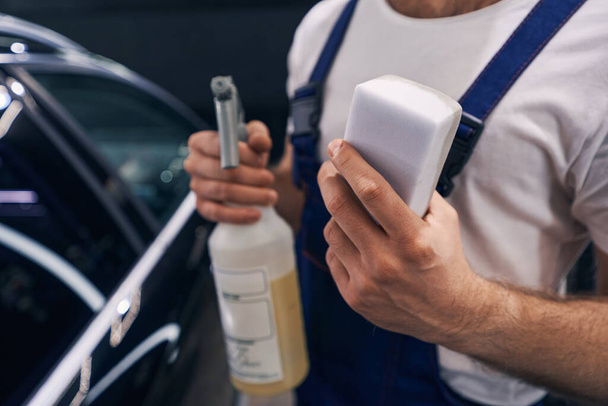 White sponge in hand of man in car repair workshop - Фото, изображение