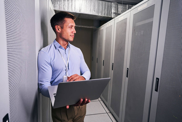 Tranquil data center worker with laptop looking away - Foto, immagini