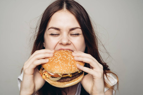 woman with a hamburger in her hands a snack fast food close-up - Фото, изображение