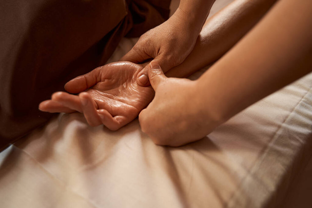Massage therapist stimulating reflex point on client hand - 写真・画像