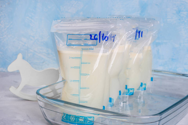 Taschen mit Muttermilch auf blauem Hintergrund. Milchbank. Muttermilch ausdrücken. Stillen. Einfrieren und Lagern von Milch. Spenden. - Foto, Bild