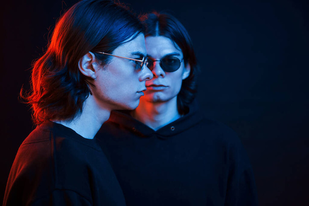 Serious people. Portrait of twin brothers. Studio shot in dark studio with neon light. - Fotoğraf, Görsel