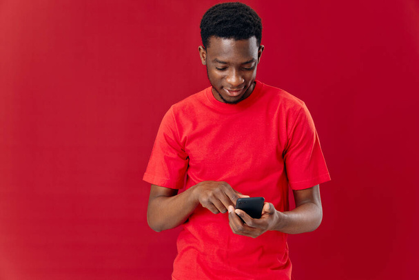 мужчина в красной футболке с телефоном в руках, передающий эмоции - Фото, изображение