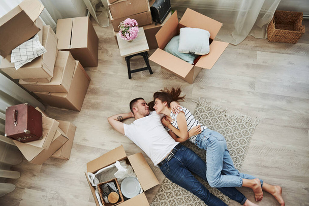 Taking a rest. Lying down on the floor. Cheerful young couple in their new apartment. Conception of moving. - Foto, Imagem