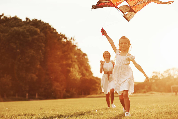 Mother and daughter have fun with kite in the field. Beautiful nature. - Φωτογραφία, εικόνα