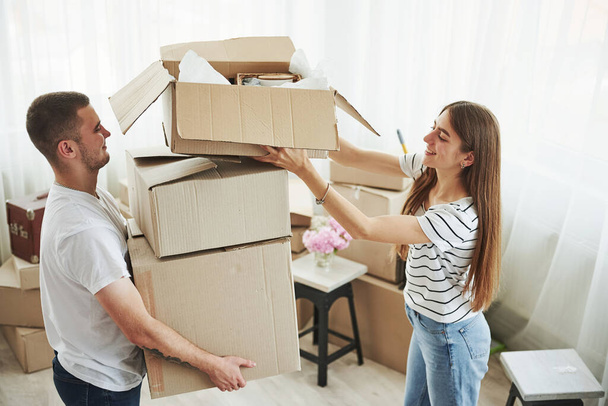 A lot of boxes. Cheerful young couple in their new apartment. Conception of moving. - Valokuva, kuva