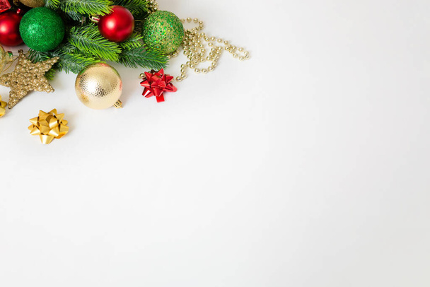 Χριστουγεννιάτικο φόντο με κλαδιά ελάτης, κόκκινα και χρυσά διακοσμητικά σε λευκό φόντο. Επίπεδη. κάτοψη με χώρο αντιγραφής. banner - Φωτογραφία, εικόνα