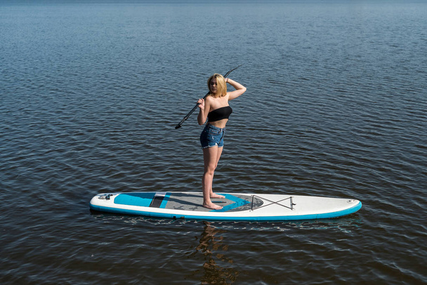  όμορφη κοπέλα το καλοκαίρι στηρίζεται σε sup board on the water, έννοια του ενεργού τρόπου ζωής  - Φωτογραφία, εικόνα