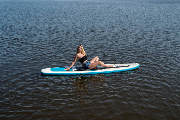 pretty young woman lying on a SUP board on hot summer day. freedom - Photo, Image