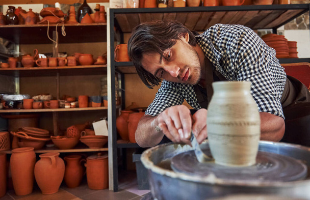 Detailing by special tool. Ceramist uses potter's wheel and creates a handmade clay product. - Fotó, kép