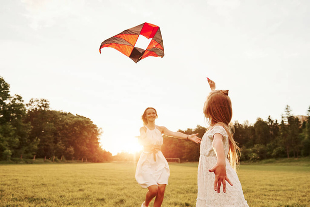 Time for a hugs. Mother and daughter have fun with kite in the field. Beautiful nature. - Valokuva, kuva