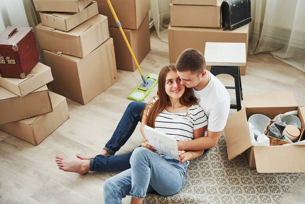 Reading document. Cheerful young couple in their new apartment. Conception of moving. - Foto, Imagem