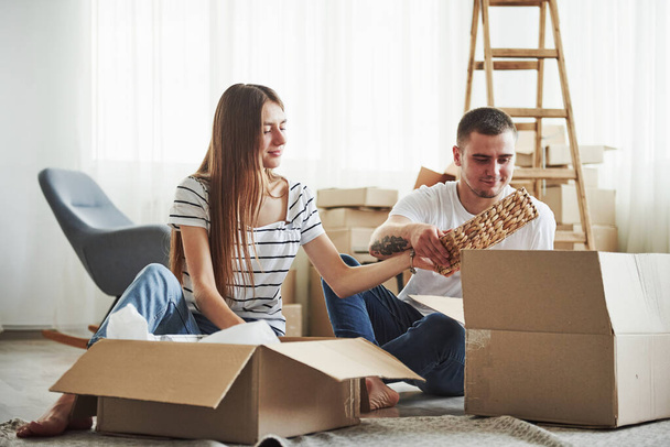 Time to unpack those boxes. Cheerful young couple in their new apartment. Conception of moving. - Фото, изображение