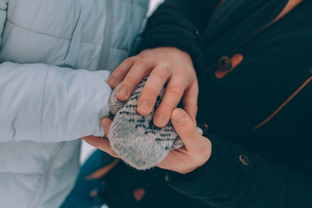 ζευγάρι κρατήσει τα χέρια σε ζεστά ρούχα. χειμερινό θέμα. - Φωτογραφία, εικόνα