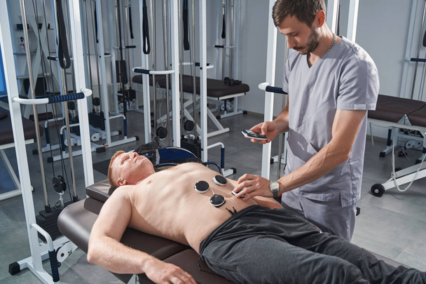 Electrostimulator massage of man stomach with therapist. Rehab - Photo, Image
