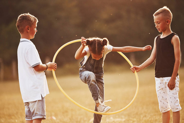 Jumping through the circle fitness tool. Kids having fun in the field. - Photo, image