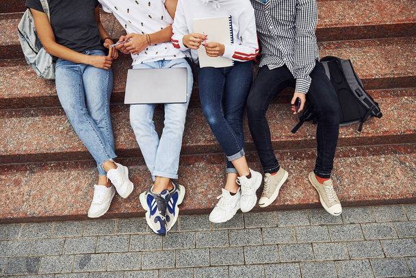 Cropped photo. Top view. Group of young students in casual clothes near university at daytime. - 写真・画像