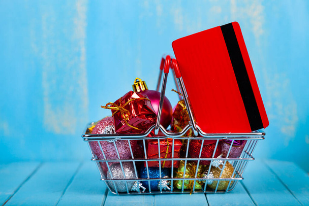 Shopping basket with Christmas gifts, decor and credit card on a blue wooden background. Christmas sale. - Foto, immagini