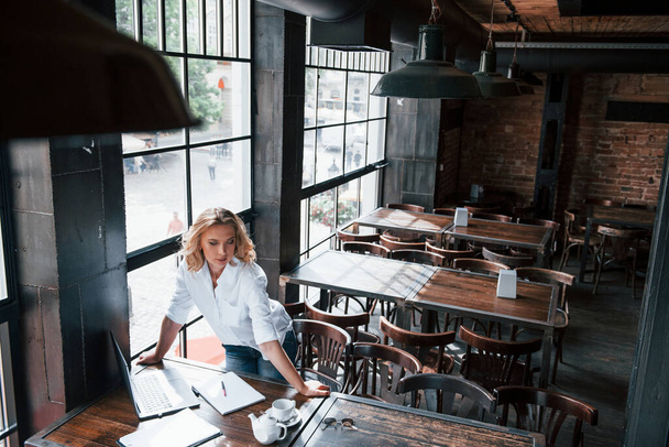 Ready for the work. Businesswoman with curly blonde hair indoors in cafe at daytime. - 写真・画像