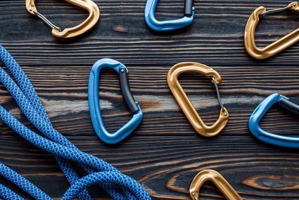 In random order. Isolated photo of climbing equipment. Part of carabiner lying on the wooden table. - Foto, Imagen