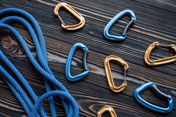 Here's your pack. Isolated photo of climbing equipment. Part of carabiner lying on the wooden table. - 写真・画像