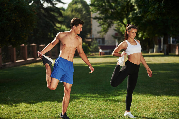 Guys have nice abs. Man and woman have fitness day in the city at daytime in the park. - Фото, зображення