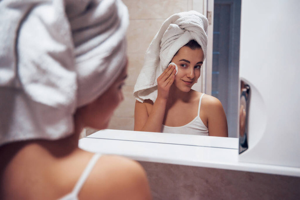 In the bathroom. Woman in white towel in head have care of herself. - Foto, imagen