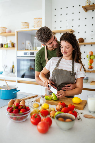 Happy young couple have fun in kitchen while preparing fresh organic food - Photo, image
