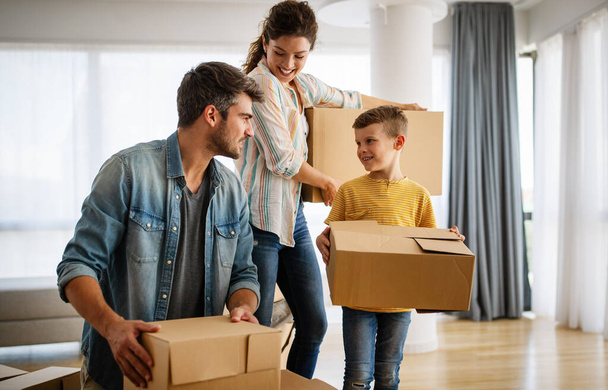 Happy family unpacking boxes in new home on moving day. People, real estate, new home concept - Foto, Bild