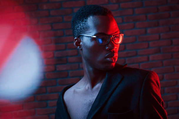 Light blinks. Futuristic neon. Young african american man in the studio. - Photo, Image