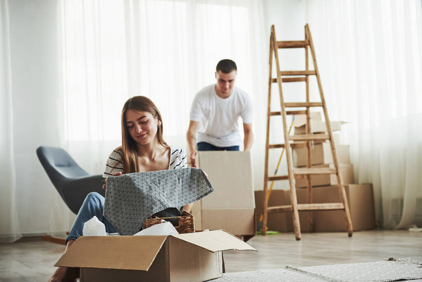 Time to unpack those boxes. Cheerful young couple in their new apartment. Conception of moving. - Foto, afbeelding