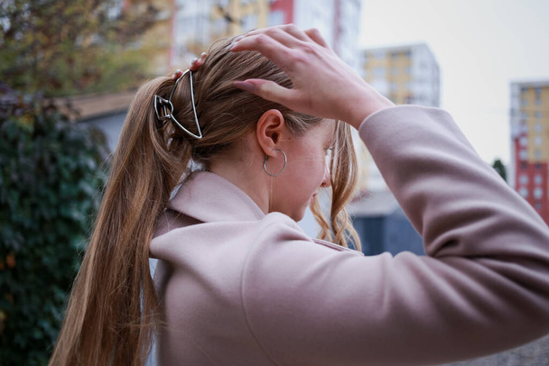 Girl straightens her hair with a barrette with her hand - Φωτογραφία, εικόνα