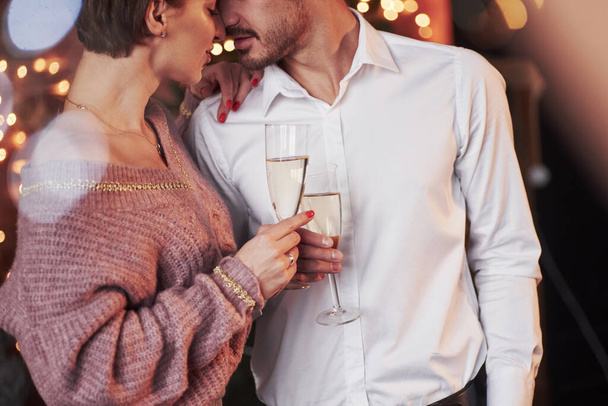 Champagne and love. Nice couple celebrating new year indoors with classic beautiful clothes on them. - Valokuva, kuva