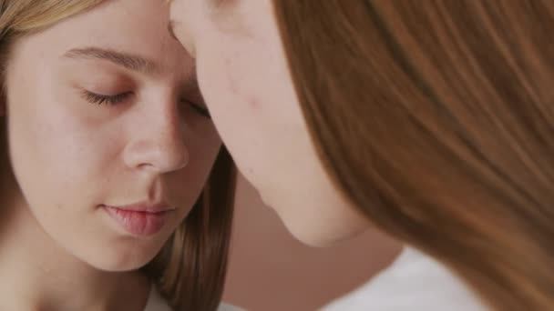 Extreme Nahaufnahme von jungen Zwillingsmädchen, die ihre Stirn berühren und mit geschlossenen Augen dastehen - Filmmaterial, Video