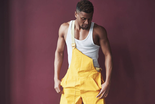 El hombre moderno a la moda. Joven afroamericano trabajador en el uniforme amarillo tienen algún trabajo. - Foto, imagen
