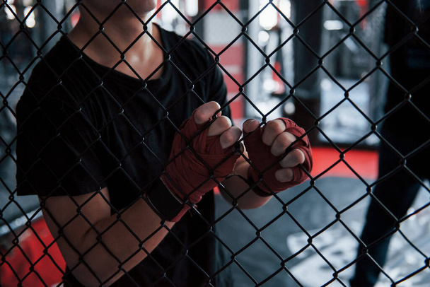 Tomando un descanso. El deportista del ring de boxeo hace ejercicio. Apoyado en la valla. - Foto, imagen